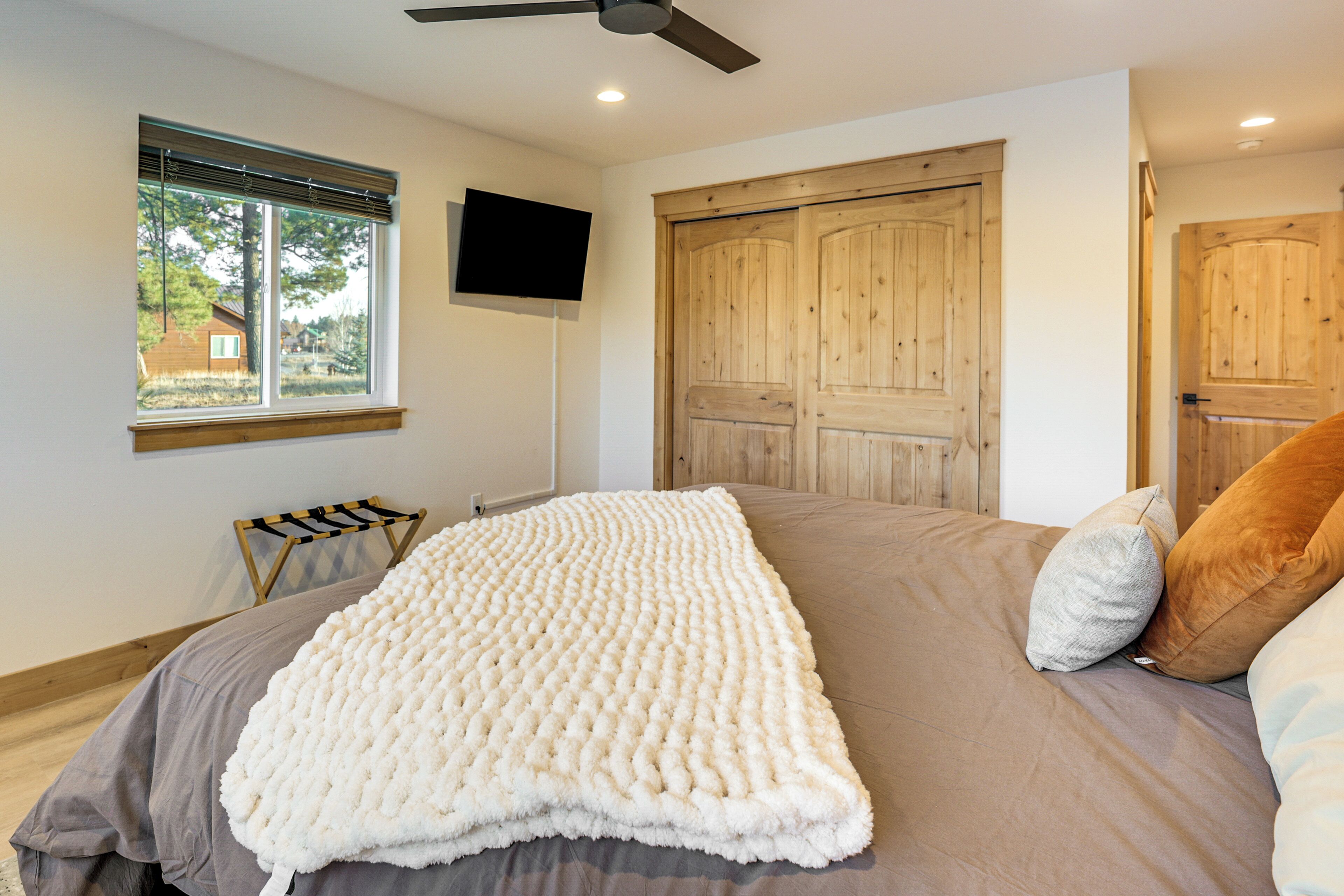 Un dormitorio con una cama grande, un ventilador de techo, una puerta de madera y una ventana con persianas.