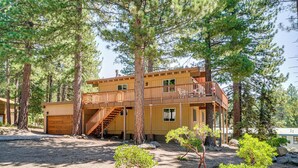 A two-story cabin with a wooden deck, surrounded by tall pine trees. - Walk to Lake Tahoe: Family Retreat w/ Deck! (Incline Village)