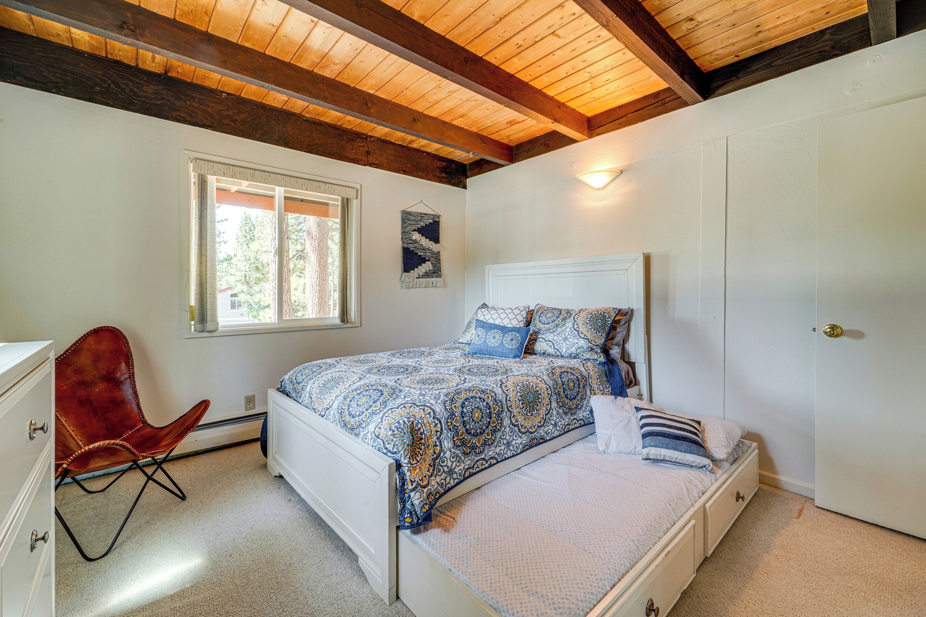 Un dormitorio con cama, una silla, una ventana y una puerta.