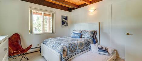 Un dormitorio con cama, una silla, una ventana y una puerta.