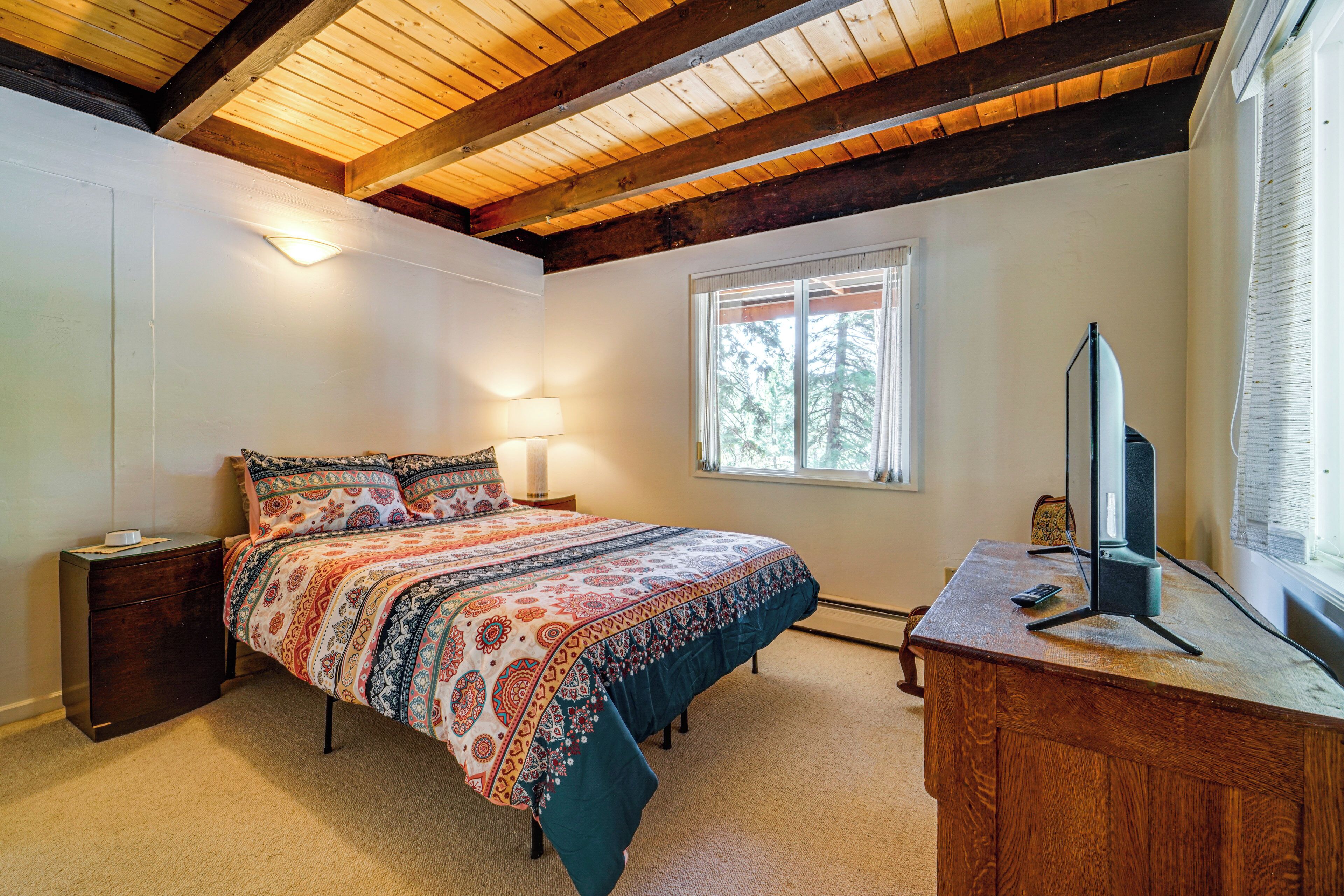Un dormitorio con cama, mesita de noche, lámpara y un escritorio con ordenador.