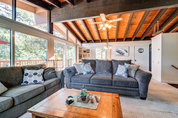 A spacious living room with a large gray sofa, a wooden coffee table, and a ceiling fan.