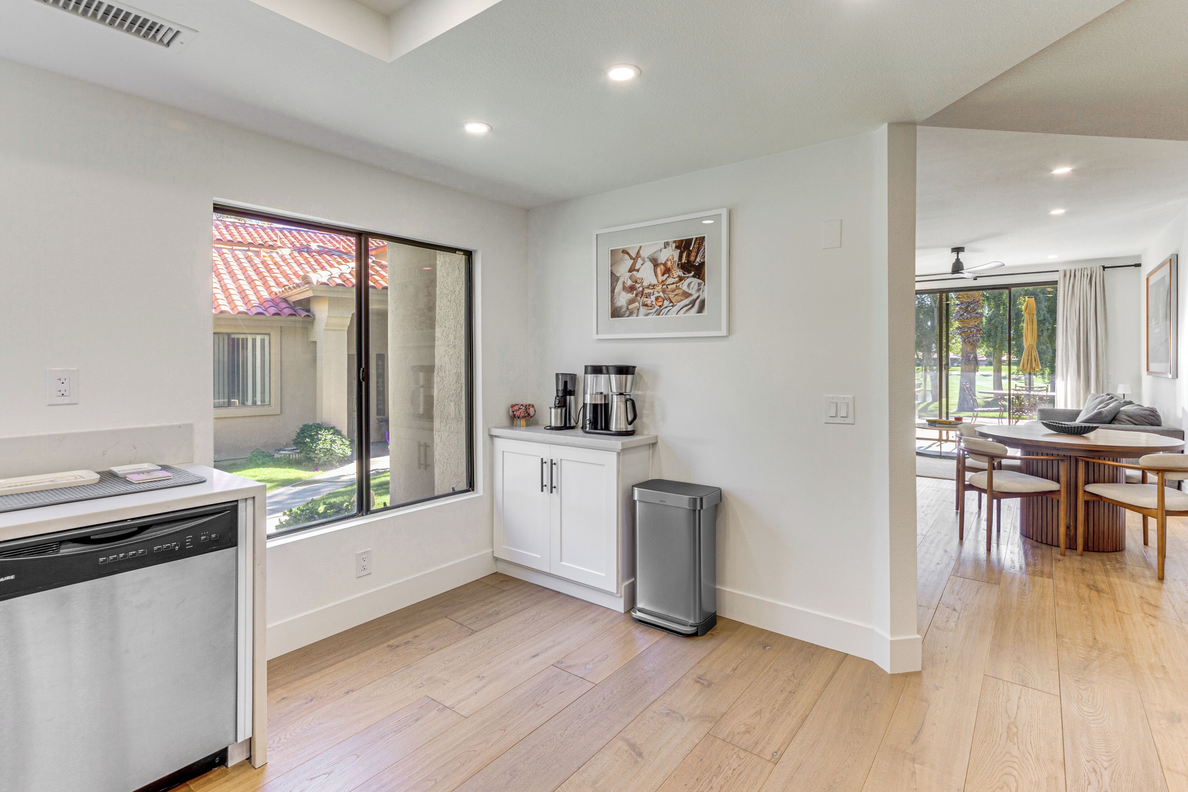 A modern kitchen with a dishwasher, a coffee maker, and a trash can.