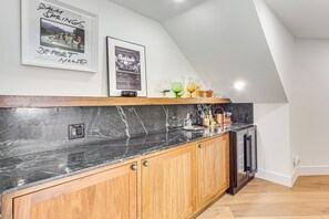 Une cuisine avec des meubles en bois, un plan de travail en marbre noir et un lave-vaisselle encastré.