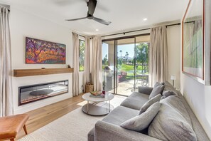 Una sala de estar moderna con chimenea, un sofá grande, una mesa de centro y vistas al exterior.