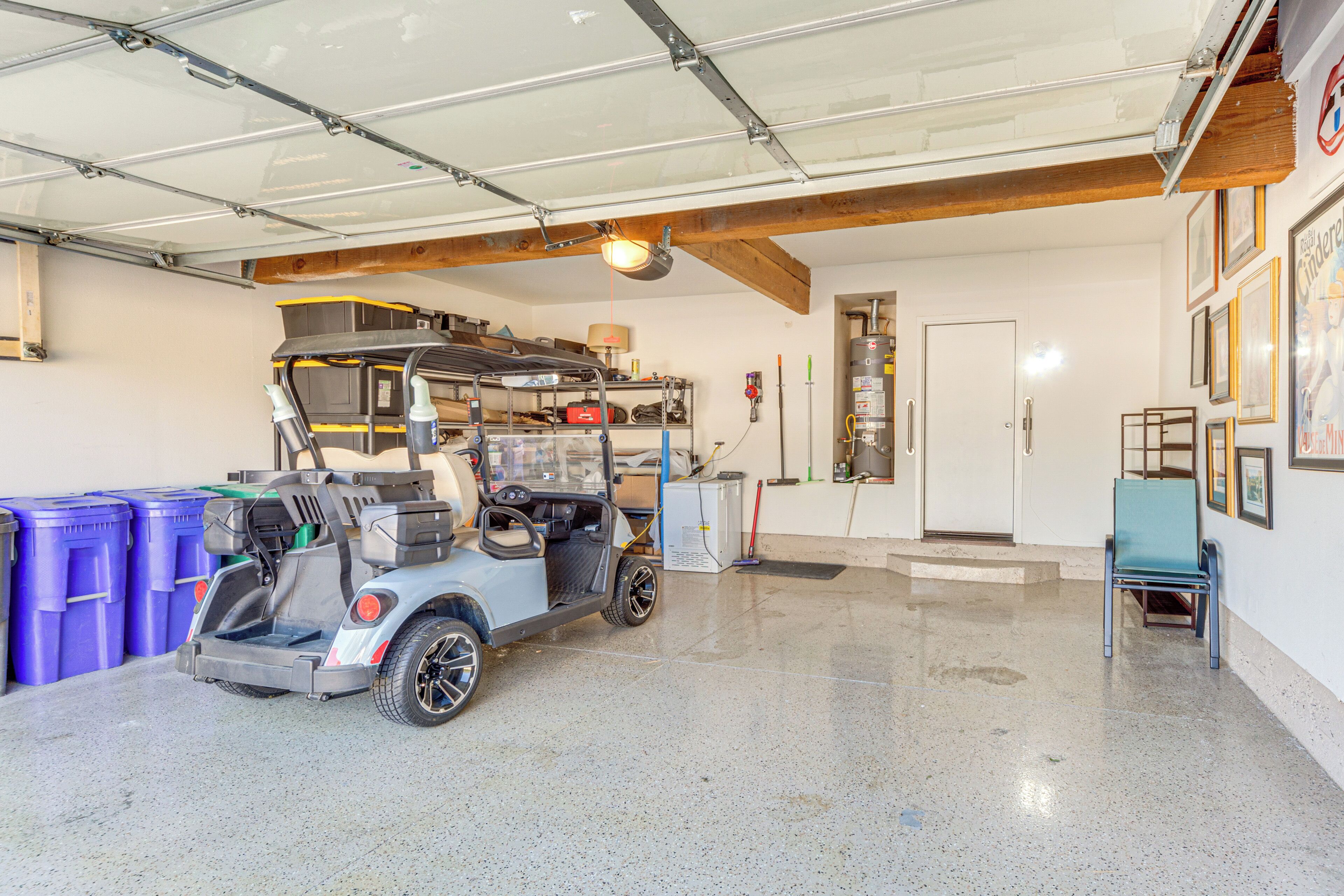 A garage with a golf cart, storage bins, and a door leading to another room.