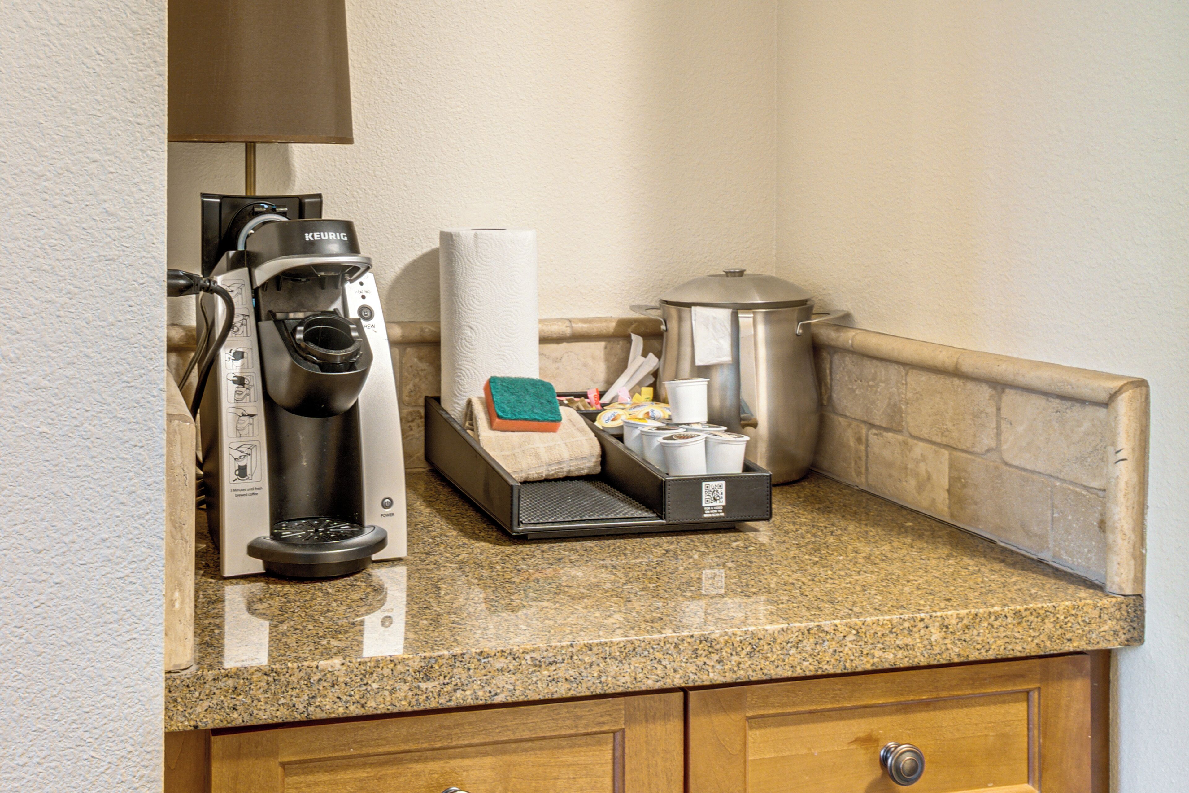 Una kitchenette con una macchina da caffè Keurig, un dispenser di carta assorbente, una caffettiera e un forno a microonde.