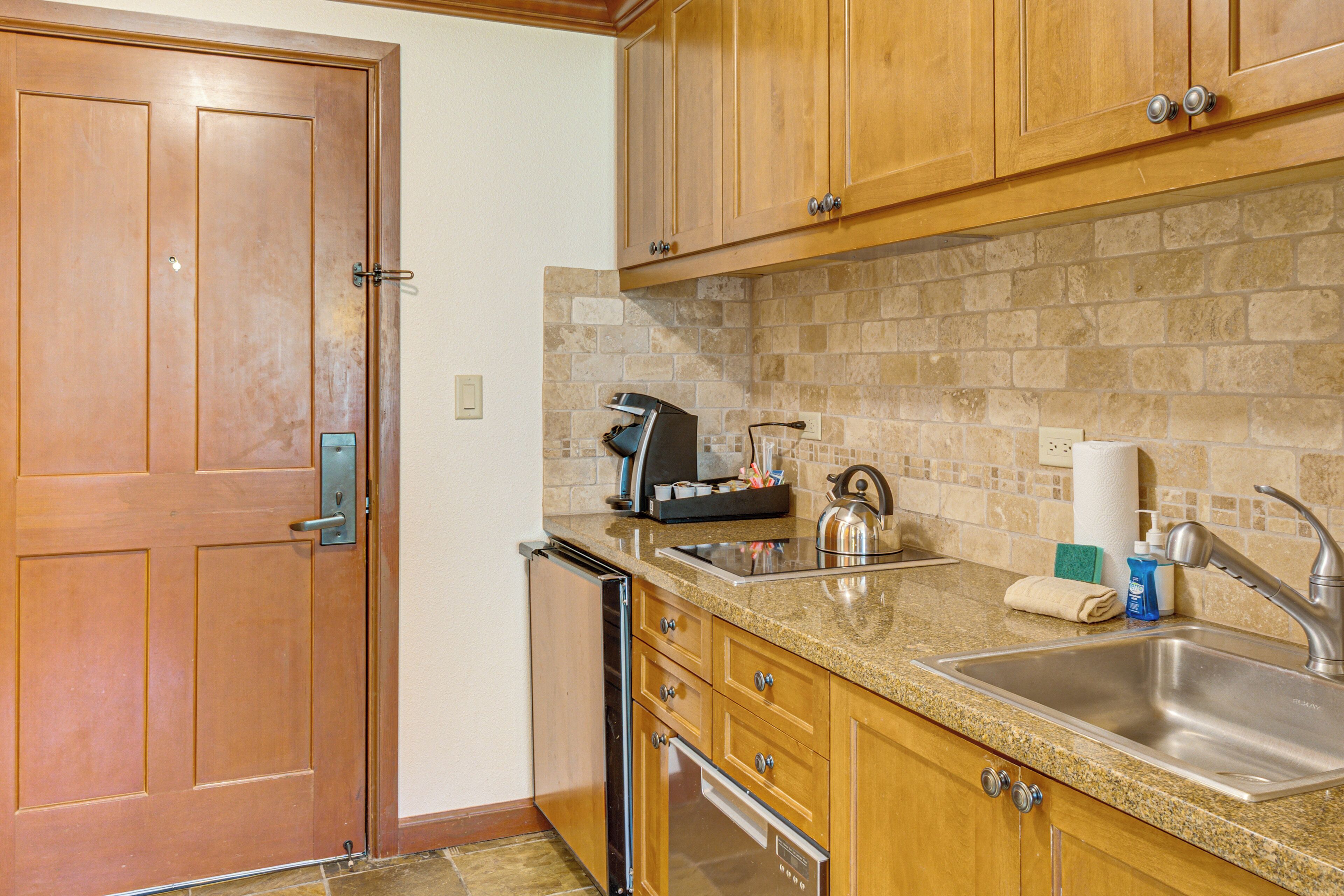 A kitchen with wooden cabinets, a stainless steel sink, a dishwasher, and a tiled backsplash.