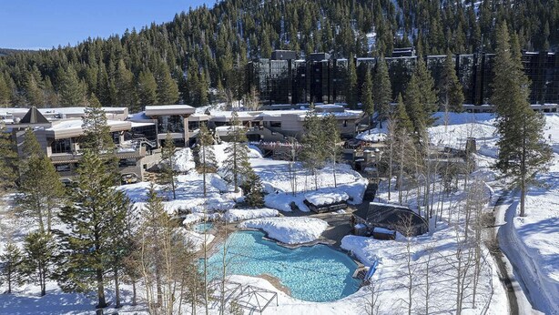 Un complexe hôtelier doté d’une piscine, de bâtiments et surplombant une forêt enneigée.