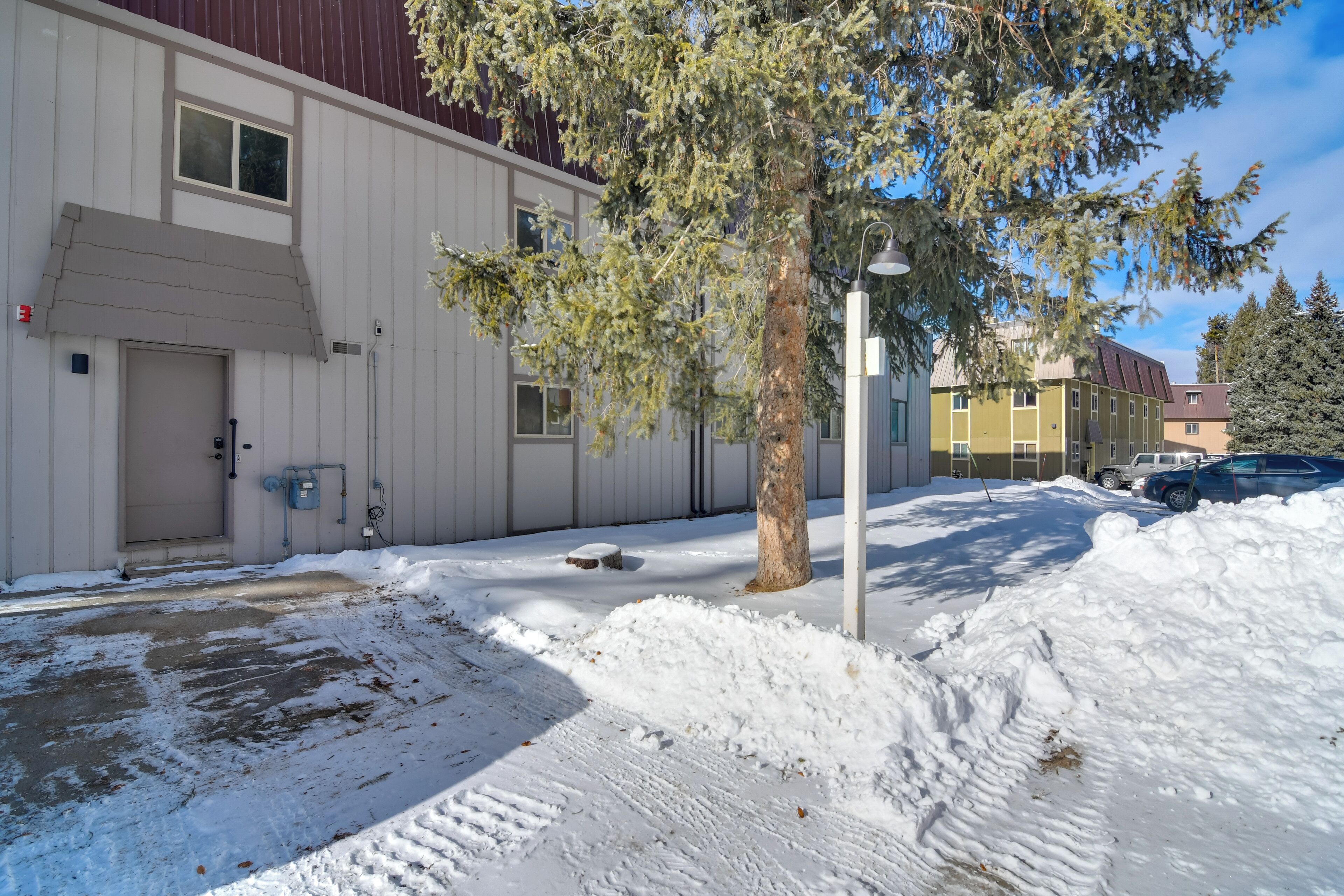 A building with a white exterior, a tree in front, and snow on the ground.