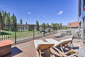 A wooden deck with lounge chairs and a hot tub, surrounded by a metal fence, overlooking a grassy area and trees. - 3 Mi to Slopes! Family-friendly Winter Park Escape (Winter Park)