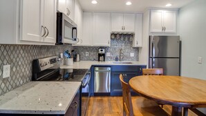 A modern kitchen with white cabinets, stainless steel appliances, and a wooden dining table. - 3 Mi to Slopes! Family-friendly Winter Park Escape (Winter Park)
