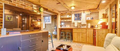 Interior acogedor de una cabaña con techo de madera, una zona de cocina, una mesa de comedor y un sofá.