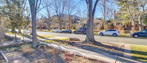 A suburban street with parked cars, trees, and houses.