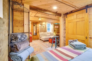 Una stanza accogliente con un letto, una poltrona e una porta in legno.