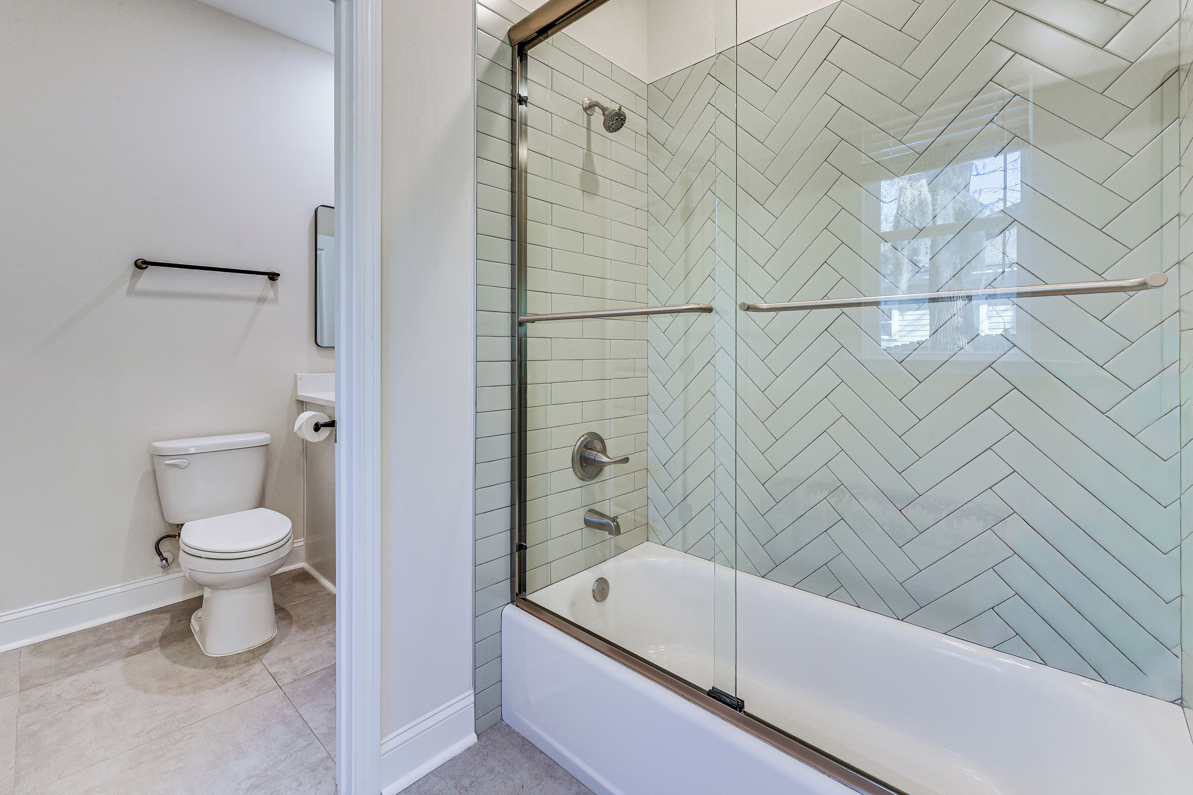A modern bathroom with a glass-enclosed shower, a toilet, and a bathtub.