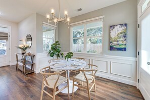A dining area with a round table, chairs, a chandelier, and a window with a view of trees. - Southern Gem Near Forsyth: Walk to Sights & Bites (Savannah)