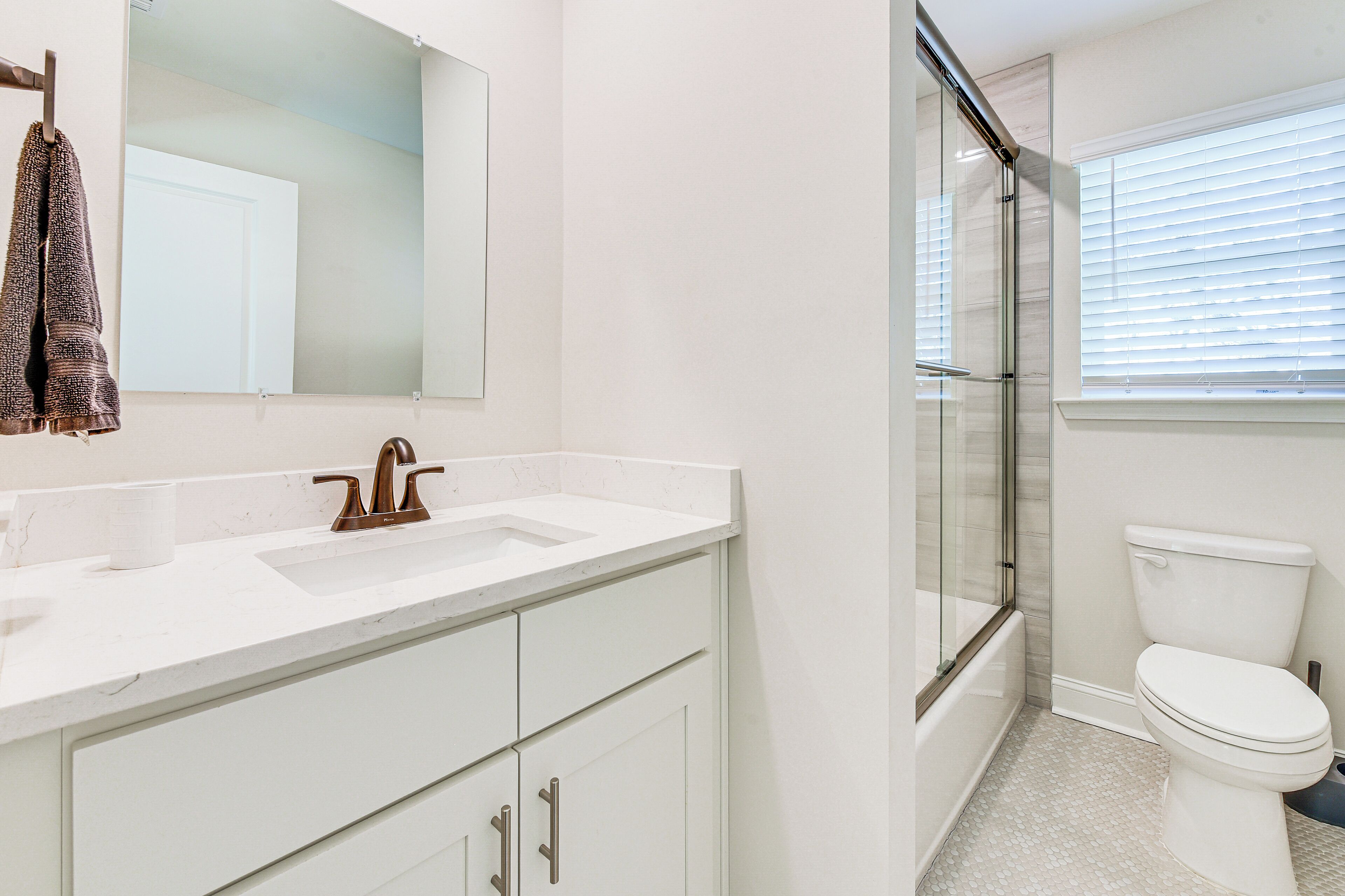 Un bagno con un lavandino bianco, uno specchio, un portascopevoli, un water e una zona doccia.