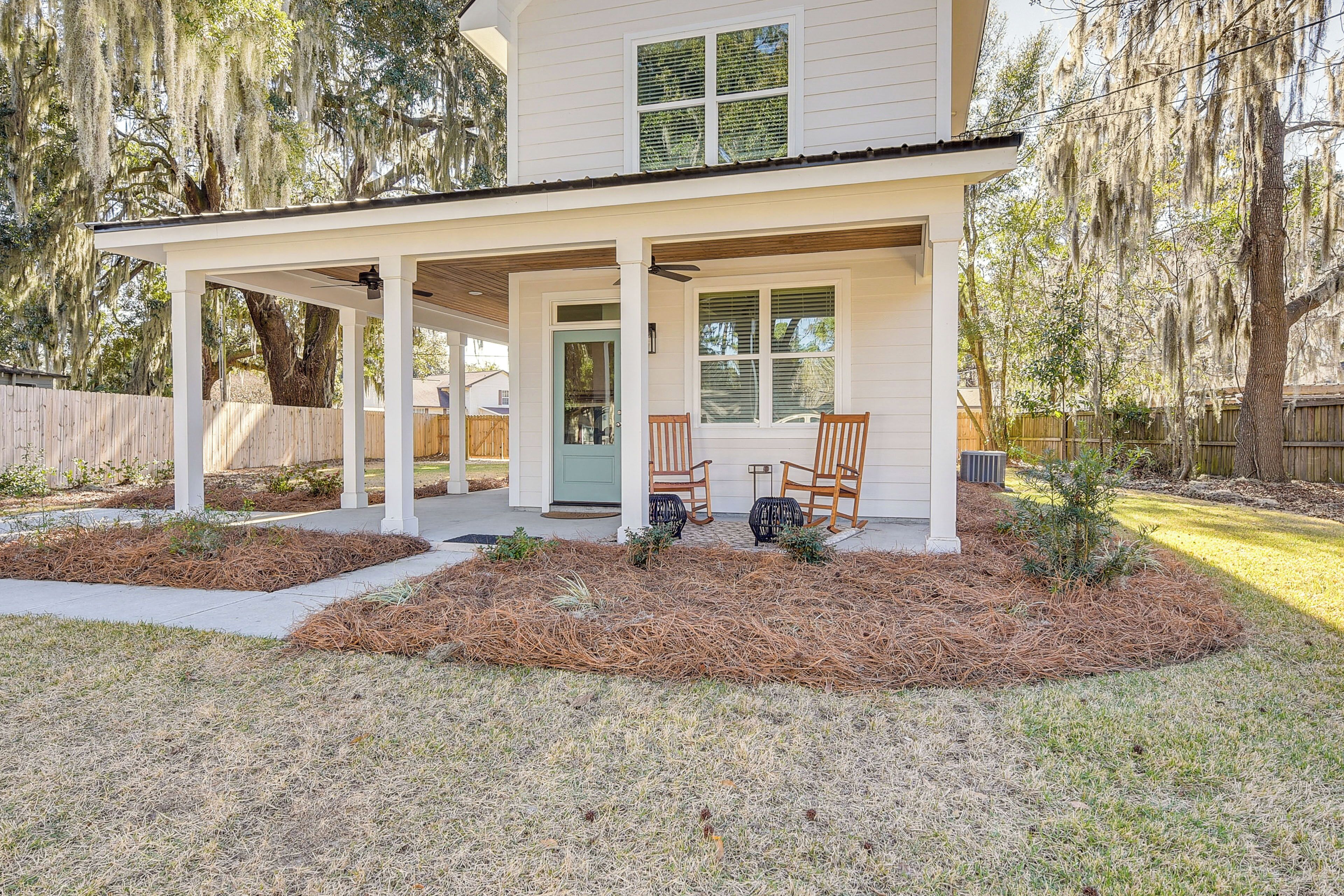 A two-story house with a covered porch, a front door, and two chairs outside.