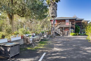 A rustic wooden building with a balcony, surrounded by lush greenery and a paved area with outdoor seating. - 'the Pickford House' - Luxury Central Coast Stay! (Cambria)