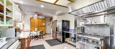 A kitchen with stainless steel appliances, wooden cabinets, and a dining area with a table and chairs.