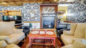 A living room with a fireplace, patterned wallpaper, and a television. - 'the Pickford House' - Luxury Central Coast Stay! (Cambria)