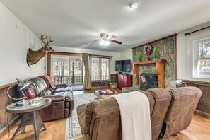 A living room with a leather sofa, a recliner, a fireplace, and a mounted deer head. - Fish & Float! Flint River Retreat w/ Pavilion (Woodland)