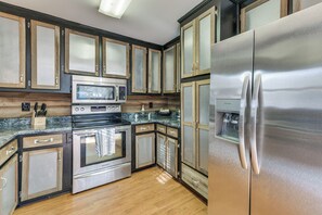 A modern kitchen with stainless steel appliances, wooden cabinets, and a granite countertop. - Fish & Float! Flint River Retreat w/ Pavilion (Woodland)