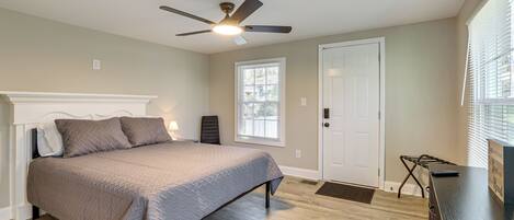 A bedroom with a bed, ceiling fan, window, door, and a dresser.