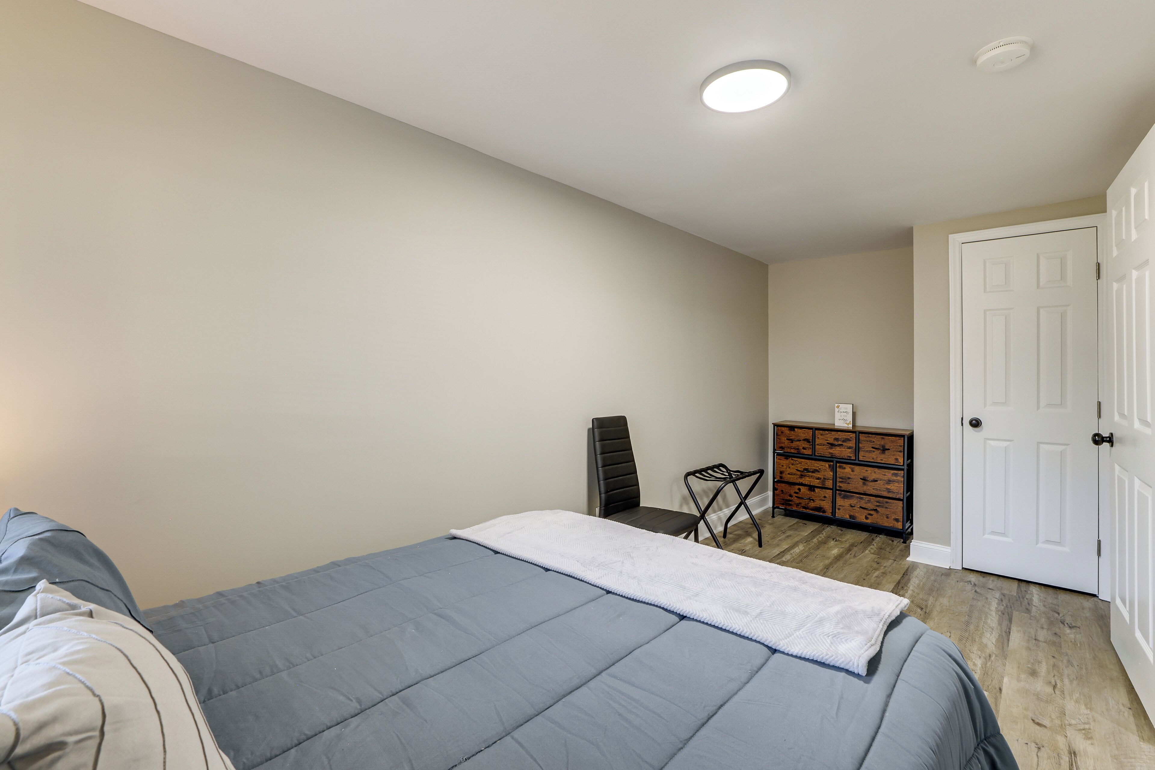 Ein Schlafzimmer mit einem Bett, einem Schminktisch, einem Stuhl und einer Tür.