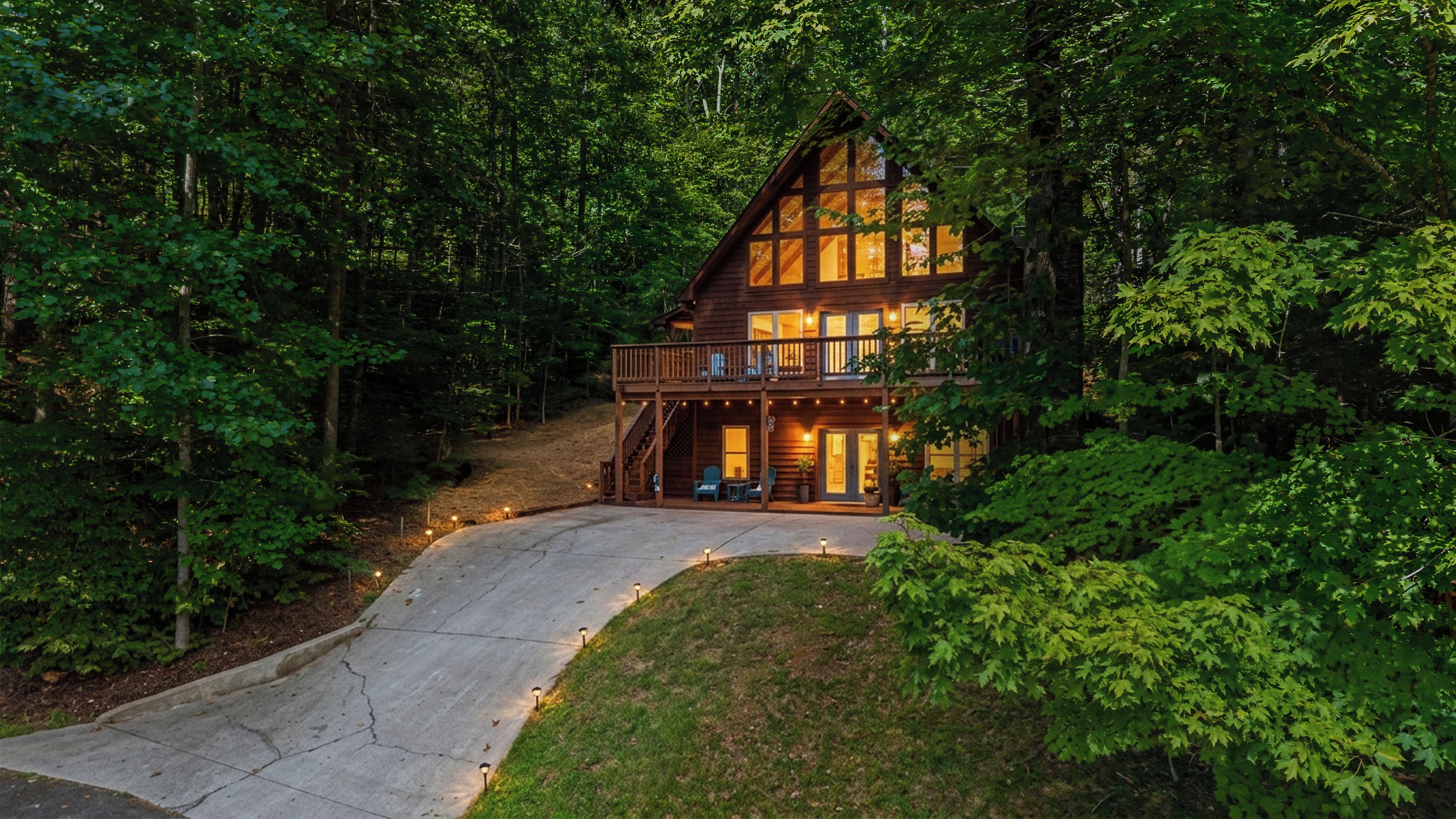 A cabin with a deck, surrounded by dense forest.