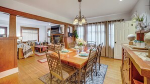 Un vaste espace dédié à la salle à manger, avec une table et des chaises en bois, un lustre et une vue sur le salon.