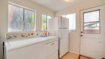 A compact kitchen with a washing machine, a refrigerator, and a door with a window.