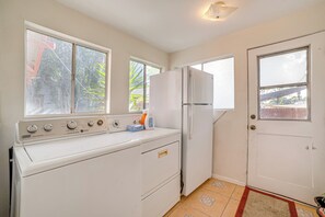Una cocina compacta con lavadora, refrigerador y una puerta con ventana.