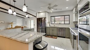 A modern kitchen with granite countertops, stainless steel appliances, and pendant lighting. - Private Beach & Pool Access! Fort Myers Getaway (Fort Myers)