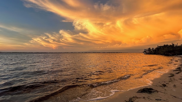 A beach with a sunset and ocean waves. - Private Beach & Pool Access! Fort Myers Getaway (Fort Myers)