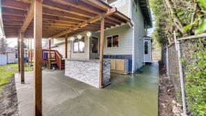 A covered outdoor patio with a stone island, wooden beams, and a view of a house with a garage. - Pet-friendly Seatac Retreat 6 Mi to Puget Sound! (SeaTac)