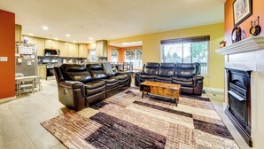 A living room with a sectional sofa, a fireplace, and a kitchen in the background. - Pet-friendly Seatac Retreat 6 Mi to Puget Sound! (SeaTac)