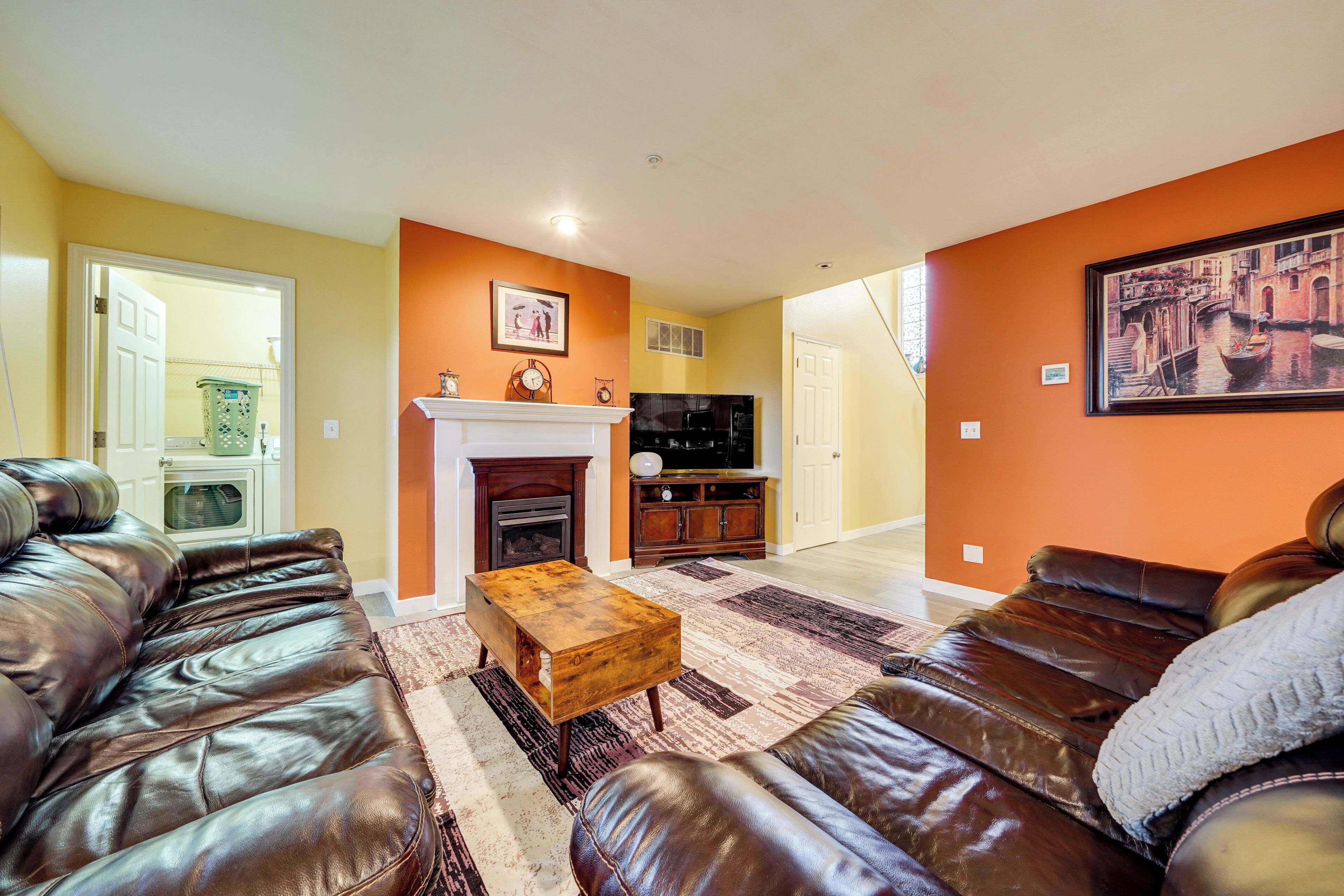A living room with leather sofas, a fireplace, and a painting of a canal scene.