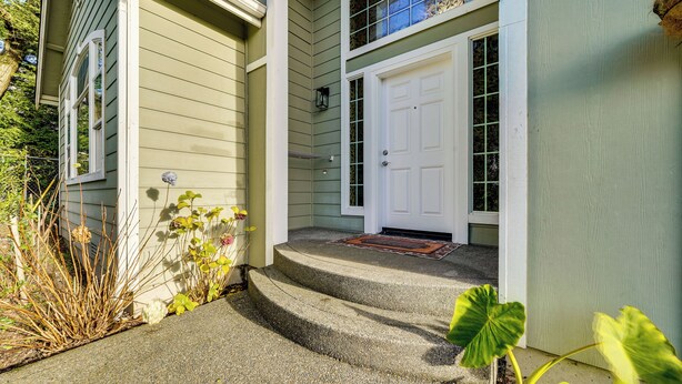 A house with a front porch, steps leading to a white door, and a small garden area with plants and a doormat. - Pet-friendly Seatac Retreat 6 Mi to Puget Sound! (SeaTac)