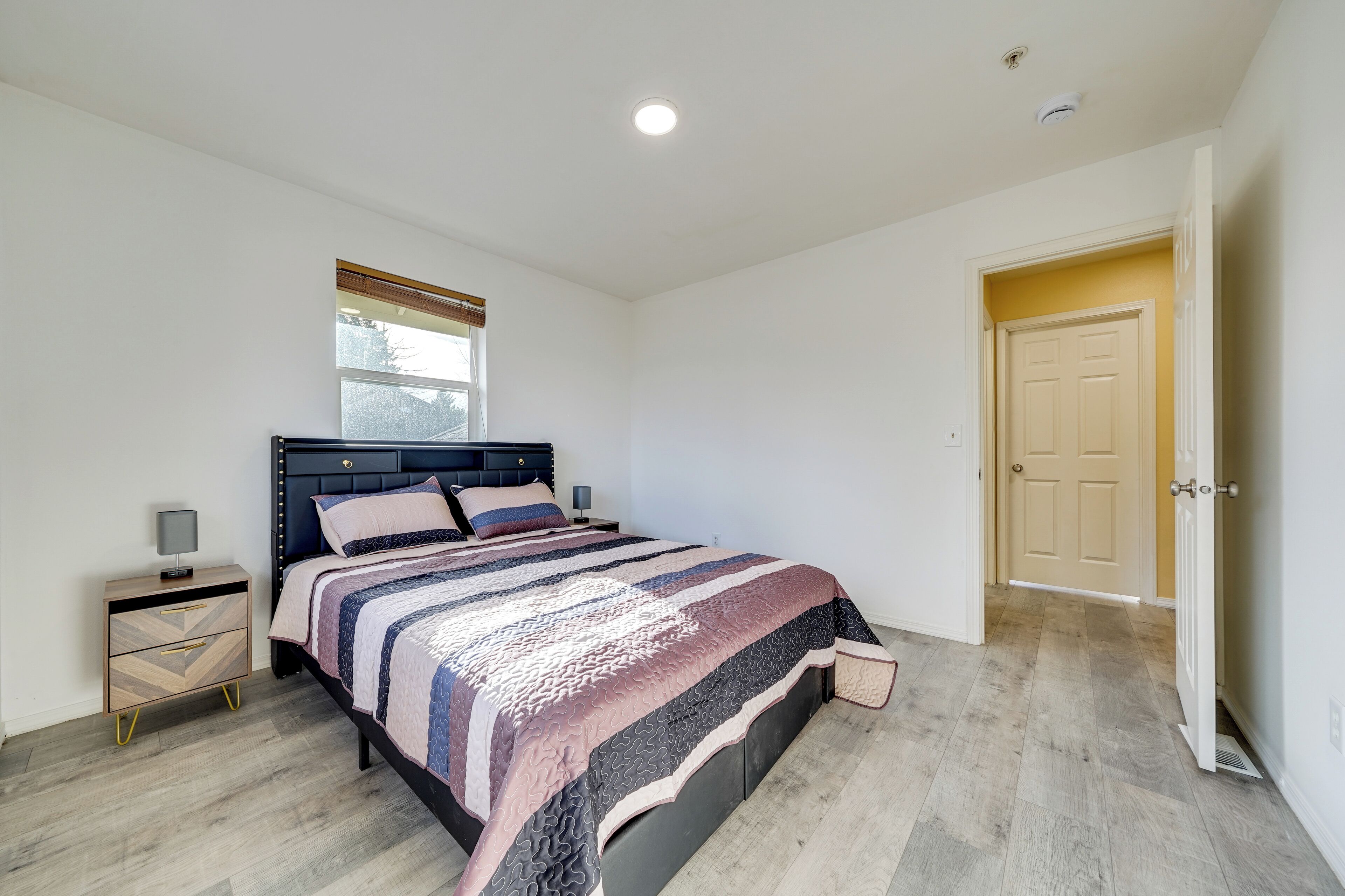 A bedroom with a bed, bedside table, and a window.