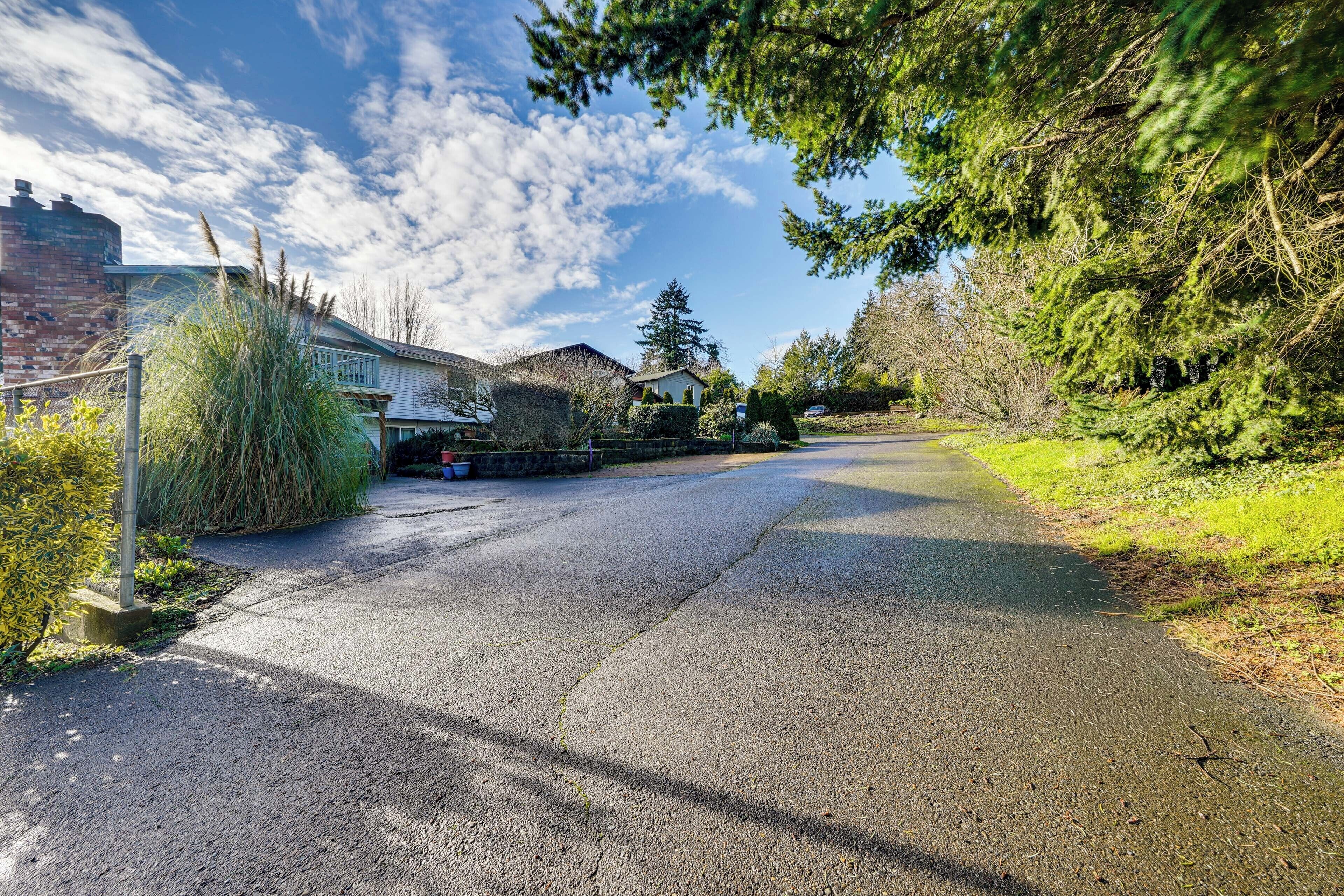 A residential street with houses, a clear sky, and greenery.