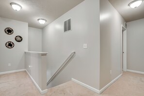 A hallway with a carpeted floor, a white wall with a vent, and three wall-mounted decorative plates. - Spacious Family Getaway w/ Yard in Kalamazoo! (Kalamazoo)