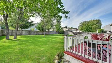 A backyard with a wooden deck, a white picket fence, and a patio area with outdoor furniture.