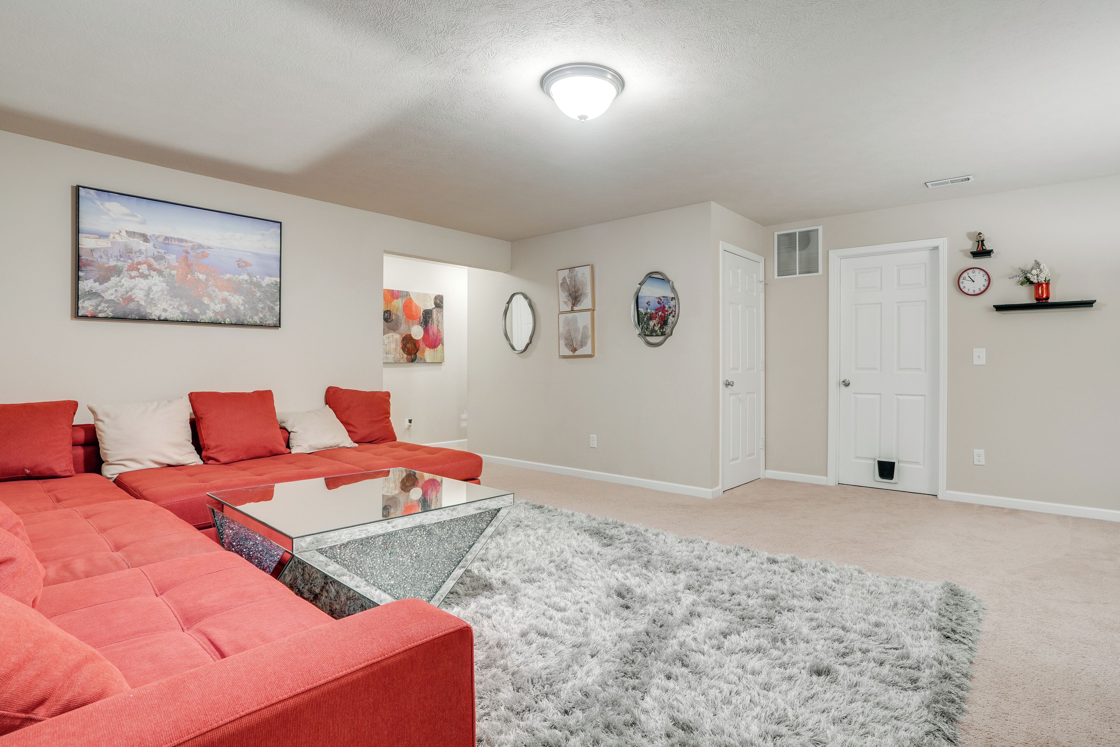 A living room with a sectional sofa, a glass coffee table, and a fluffy rug.