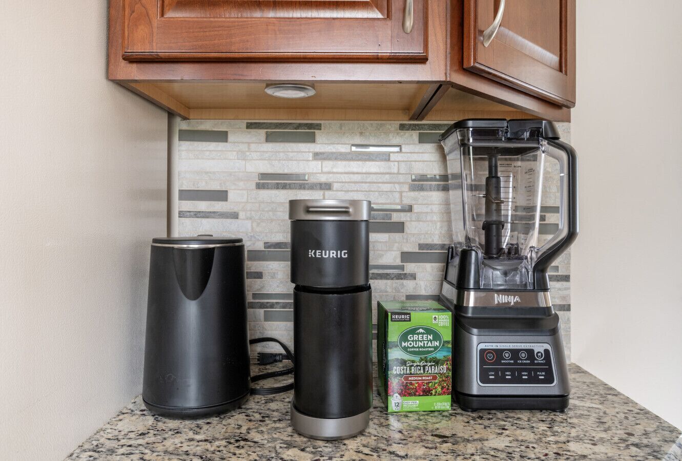 A kitchen counter with a Keurig coffee maker, a NINJA brand blender, and a box of Green Mountain Costa Rica Paraíso coffee.