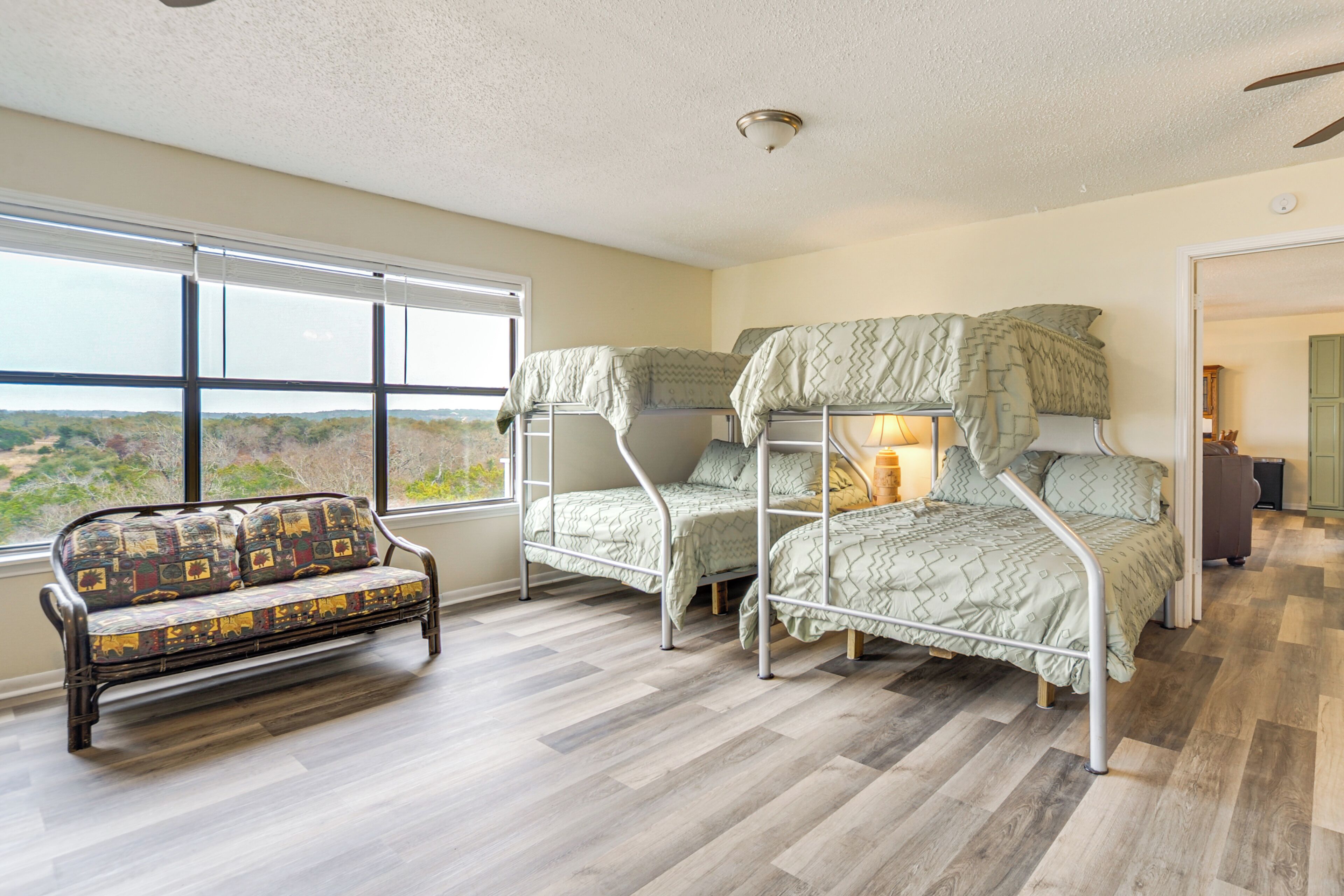 Quarto com cama de solteiro, sofá e uma ampla janela com vista para o exterior.