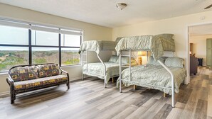 Una habitación con una cama litera, un sofá y un ventanal con vistas al exterior.