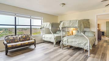 Quarto com cama de solteiro, sofá e uma ampla janela com vista para o exterior.