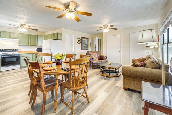 A spacious living area with a dining table, chairs, a sofa, and a coffee table. There are ceiling fans, a lamp, and a clock on the wall. - 200 Acres Pond & Pier 10-mile Hill Country Views (Blanco)